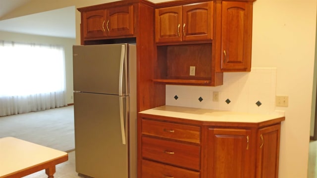 kitchen with backsplash, stainless steel refrigerator, and light carpet