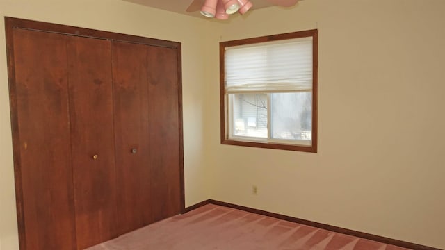 unfurnished bedroom featuring ceiling fan, light colored carpet, and a closet