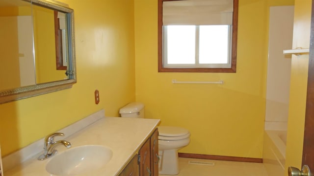 bathroom with vanity, toilet, and a tub to relax in