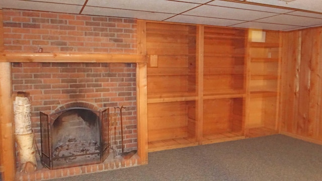 interior space with wood walls, a drop ceiling, and carpet floors