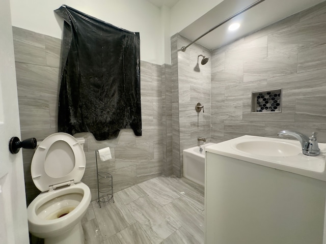 full bathroom featuring tile walls, vanity, tiled shower / bath combo, and toilet