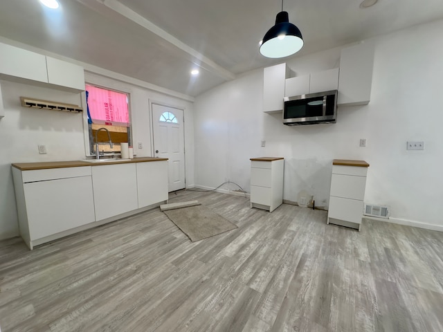 kitchen with sink, hanging light fixtures, light hardwood / wood-style flooring, lofted ceiling with beams, and white cabinets