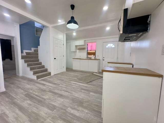 kitchen with white cabinetry, decorative light fixtures, and light wood-type flooring