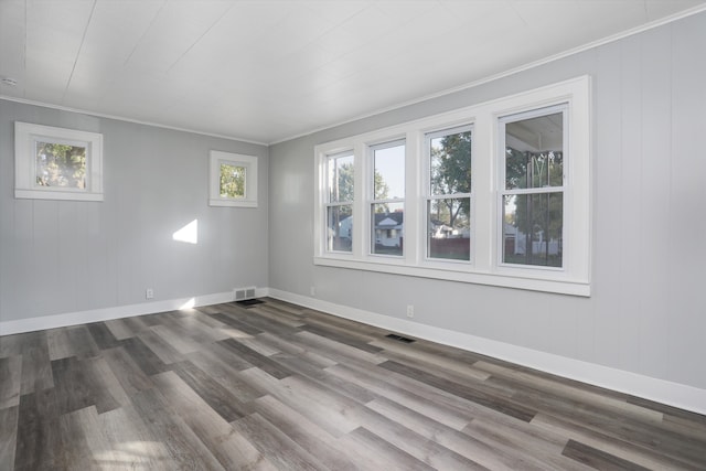 spare room with a healthy amount of sunlight, wood-type flooring, and crown molding