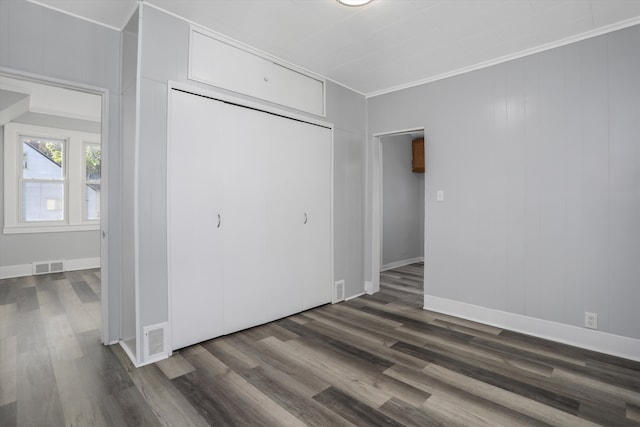 unfurnished bedroom featuring a closet, dark hardwood / wood-style floors, and ornamental molding