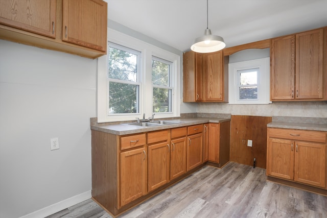 kitchen with decorative backsplash, sink, hanging light fixtures, and light hardwood / wood-style flooring