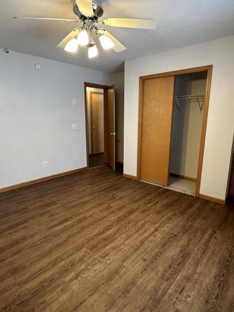 unfurnished bedroom with dark hardwood / wood-style flooring, ceiling fan, and a closet