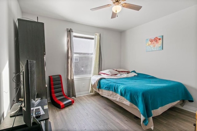 bedroom featuring hardwood / wood-style floors, ceiling fan, and multiple windows