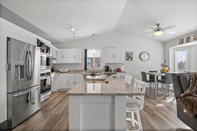 kitchen featuring hardwood / wood-style floors, appliances with stainless steel finishes, decorative light fixtures, a kitchen island, and white cabinetry