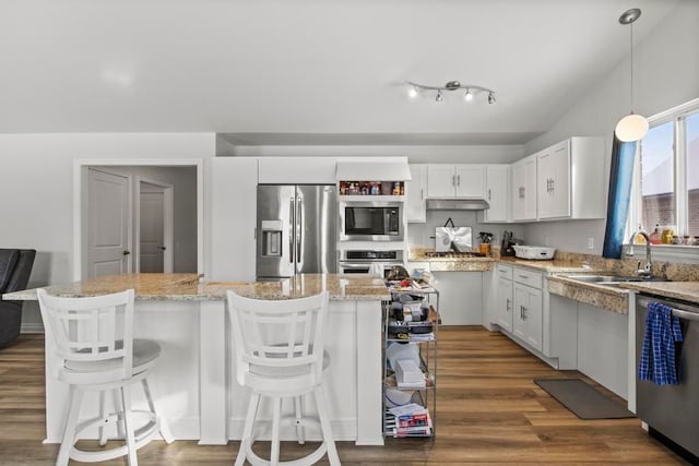 kitchen featuring a center island, stainless steel appliances, pendant lighting, a kitchen bar, and white cabinets