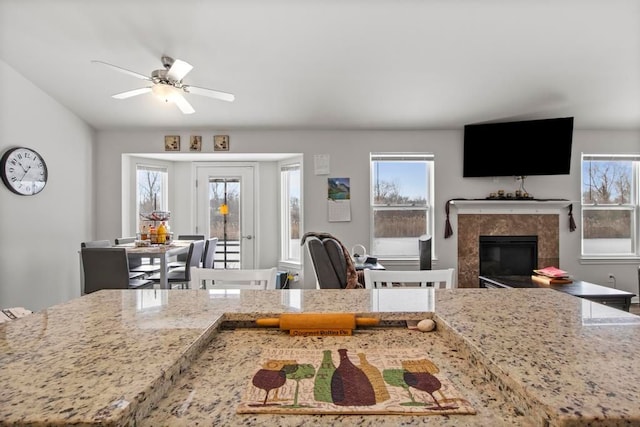 kitchen with light stone countertops, a fireplace, and ceiling fan