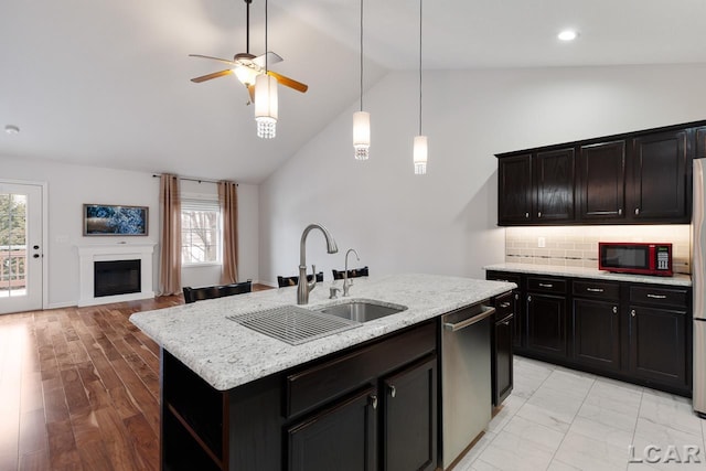 kitchen featuring sink, stainless steel dishwasher, backsplash, plenty of natural light, and an island with sink