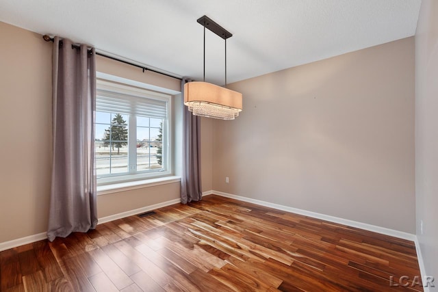 empty room featuring a chandelier and hardwood / wood-style floors