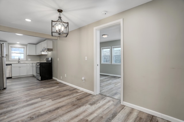 kitchen featuring a chandelier, light hardwood / wood-style floors, stainless steel appliances, hanging light fixtures, and white cabinets