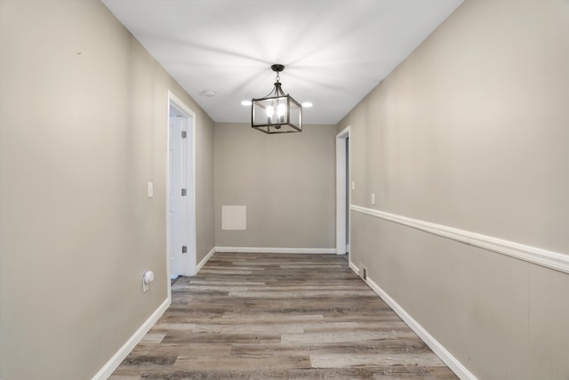 hallway with an inviting chandelier and hardwood / wood-style flooring