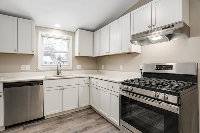 kitchen with appliances with stainless steel finishes, light hardwood / wood-style floors, white cabinetry, and sink