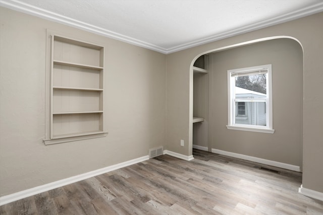 empty room with built in features and hardwood / wood-style flooring