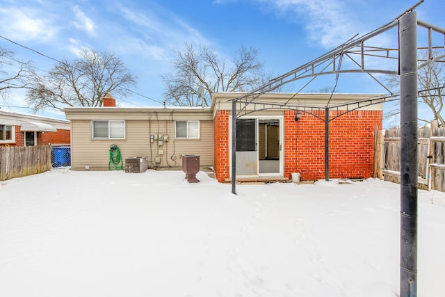 snow covered back of property featuring central AC