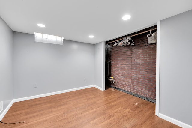 interior space with brick wall and hardwood / wood-style flooring