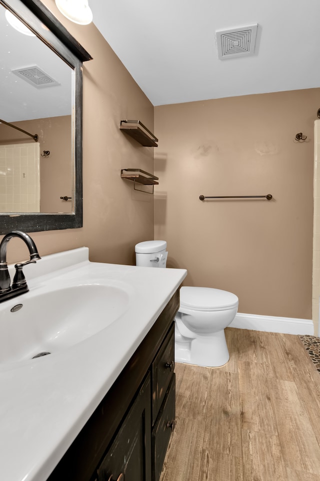 bathroom with toilet, a shower, vanity, and hardwood / wood-style floors