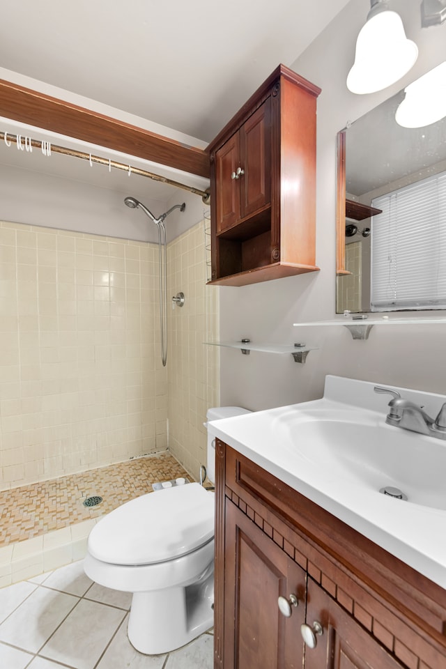 bathroom with toilet, tile patterned flooring, a tile shower, and vanity