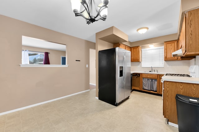 kitchen featuring range, a chandelier, hanging light fixtures, stainless steel refrigerator with ice dispenser, and sink