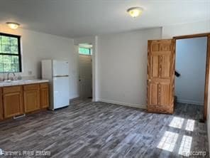 4433 Brighton Rd, Howell, MI 48843 - kitchen with freestanding refrigerator, brown cabinetry, dark wood-style flooring, a sink, and light countertops