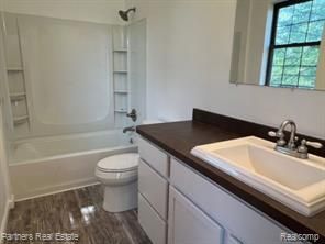 4433 Brighton Rd, Howell, MI 48843 - full bath with toilet, wood finished floors, vanity, and washtub / shower combination