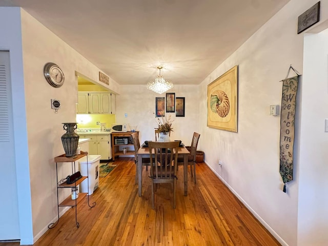 dining space with hardwood / wood-style flooring and an inviting chandelier