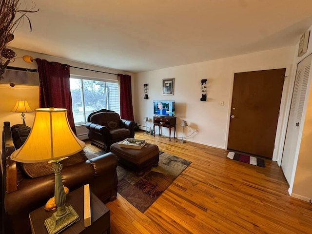 living room with wood-type flooring, an AC wall unit, and a baseboard heating unit