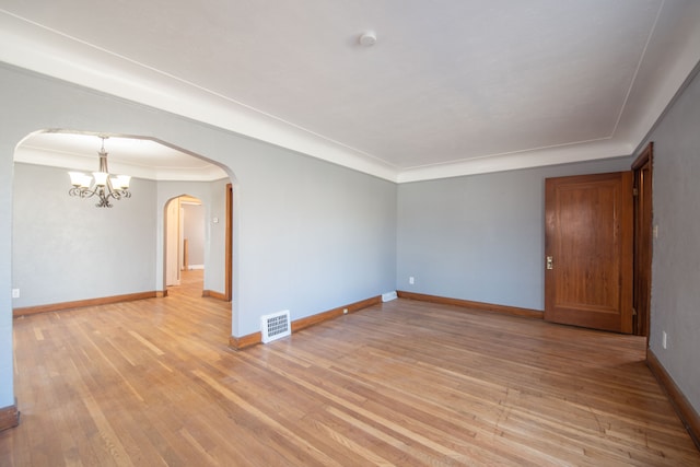 spare room with light hardwood / wood-style flooring, ornamental molding, and an inviting chandelier