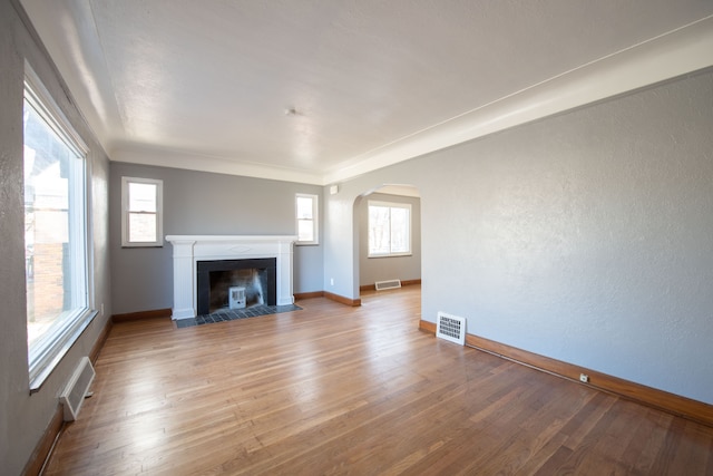 unfurnished living room with crown molding, a healthy amount of sunlight, and light hardwood / wood-style floors