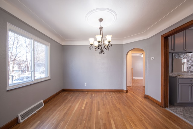 unfurnished dining area featuring a chandelier, light hardwood / wood-style flooring, and crown molding