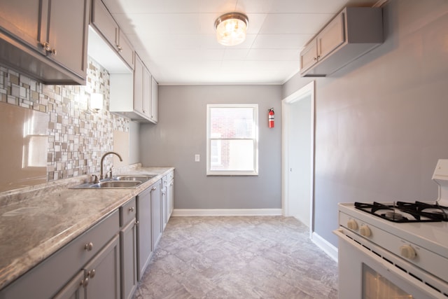 kitchen with white gas range oven, gray cabinets, and sink