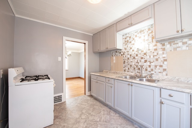 kitchen featuring decorative backsplash, white gas range, ornamental molding, and sink