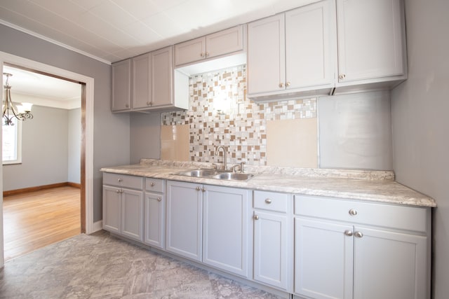 kitchen with gray cabinetry, sink, tasteful backsplash, crown molding, and decorative light fixtures