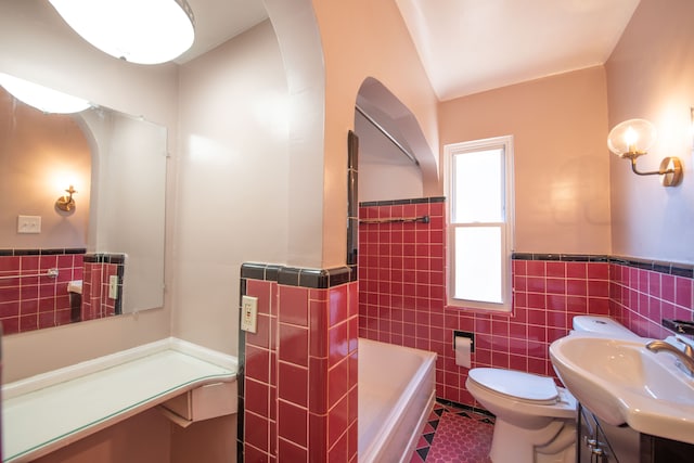 bathroom featuring vanity, tile walls, tile patterned flooring, toilet, and a bathing tub