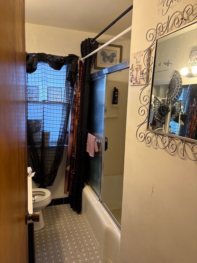 bathroom featuring combined bath / shower with glass door and toilet