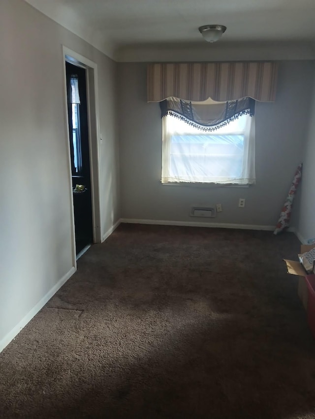 unfurnished room featuring dark colored carpet and baseboards