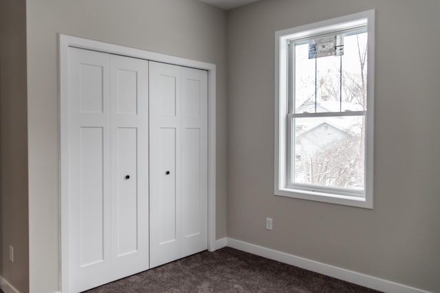 unfurnished bedroom featuring dark carpet and a closet