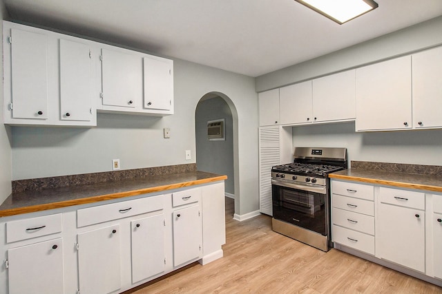 kitchen with white cabinets, light wood-type flooring, stainless steel gas stove, and a wall mounted air conditioner