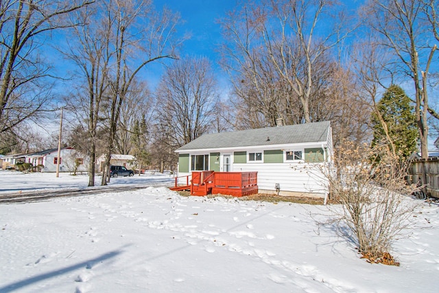 snow covered rear of property featuring a chimney and a deck