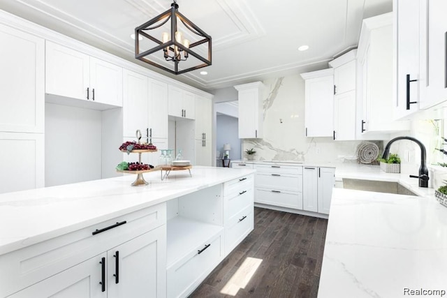 kitchen with tasteful backsplash, dark wood-type flooring, hanging light fixtures, white cabinets, and sink