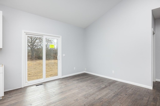 unfurnished room featuring vaulted ceiling and dark hardwood / wood-style floors