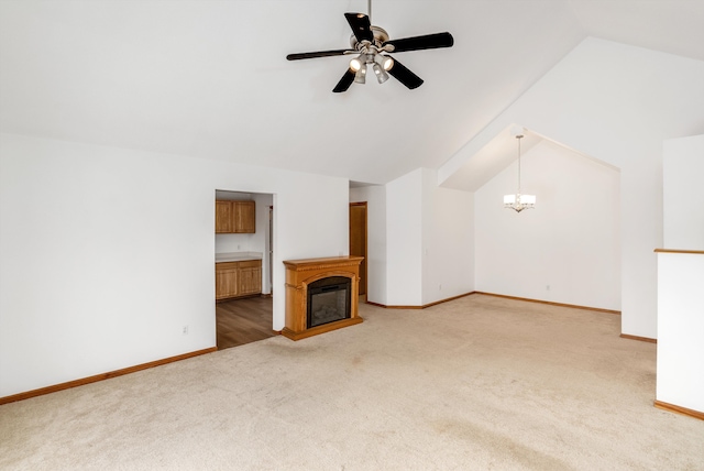 unfurnished living room featuring carpet floors, lofted ceiling, and ceiling fan with notable chandelier