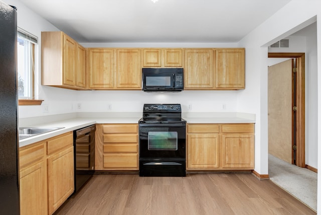 kitchen with light brown cabinetry, black appliances, and sink