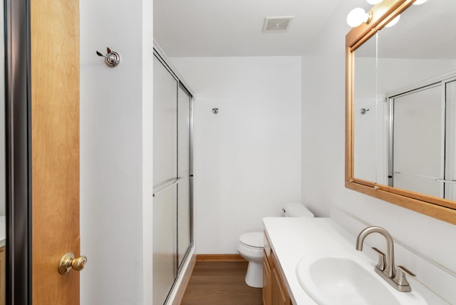 bathroom featuring toilet, an enclosed shower, vanity, and wood-type flooring