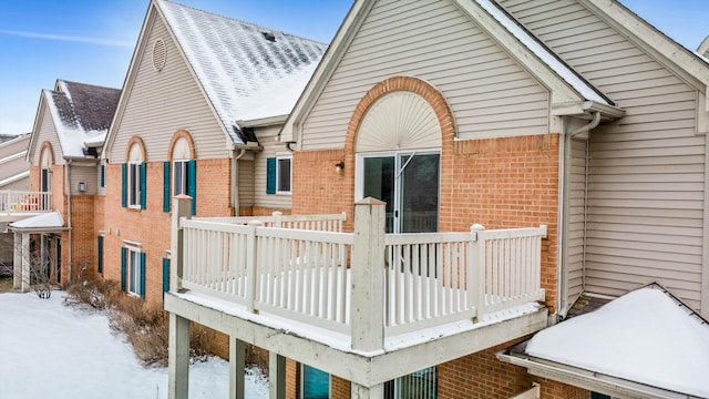 snow covered rear of property featuring a balcony