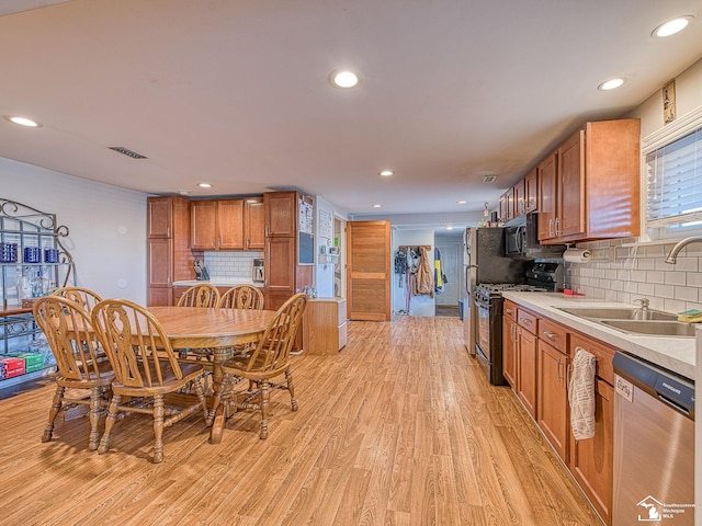 kitchen with sink, light wood-type flooring, backsplash, and black appliances