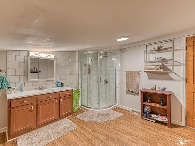 bathroom with vanity, backsplash, hardwood / wood-style flooring, and a shower with shower door